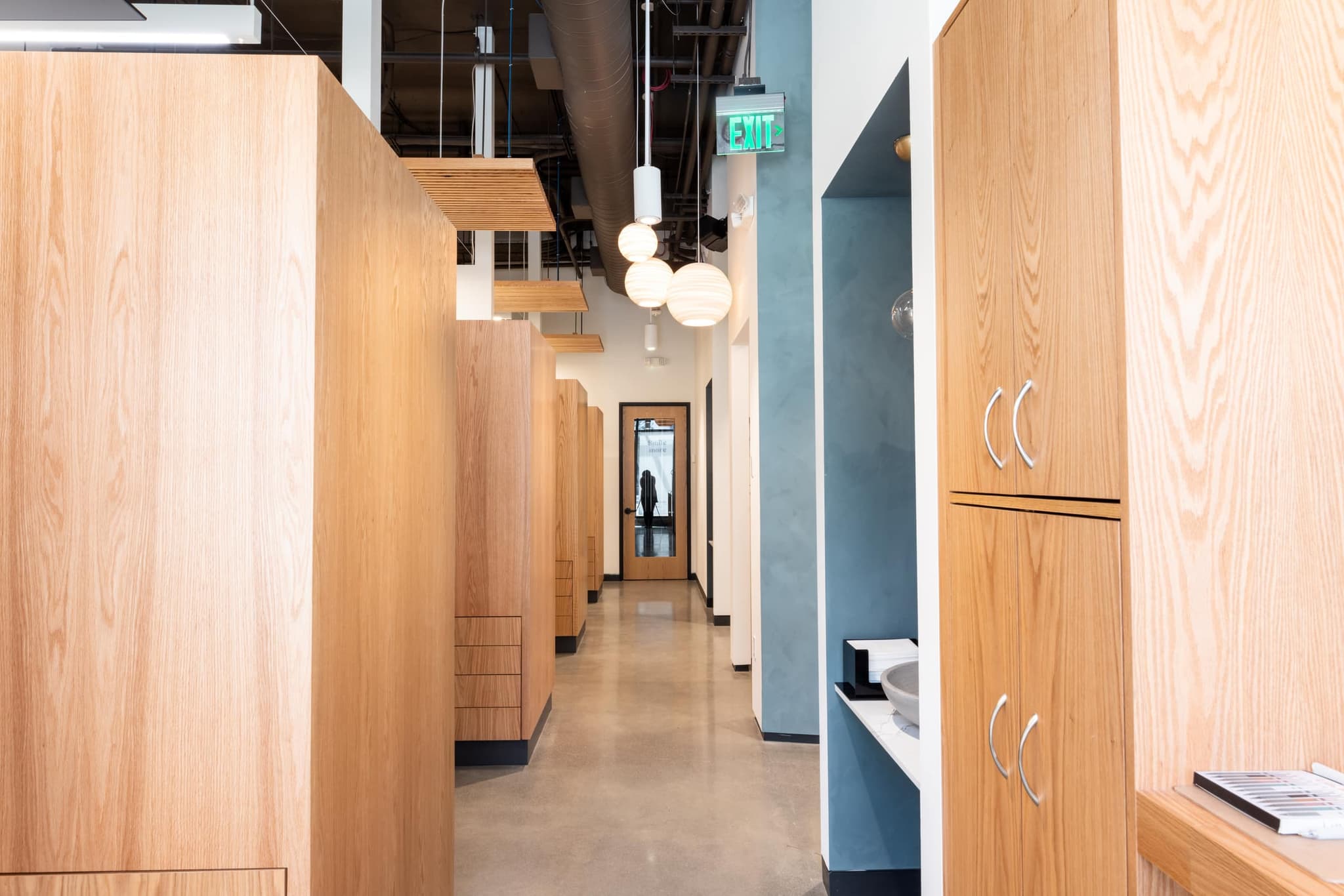 A quiet, wood-lined corridor under warm pendant light