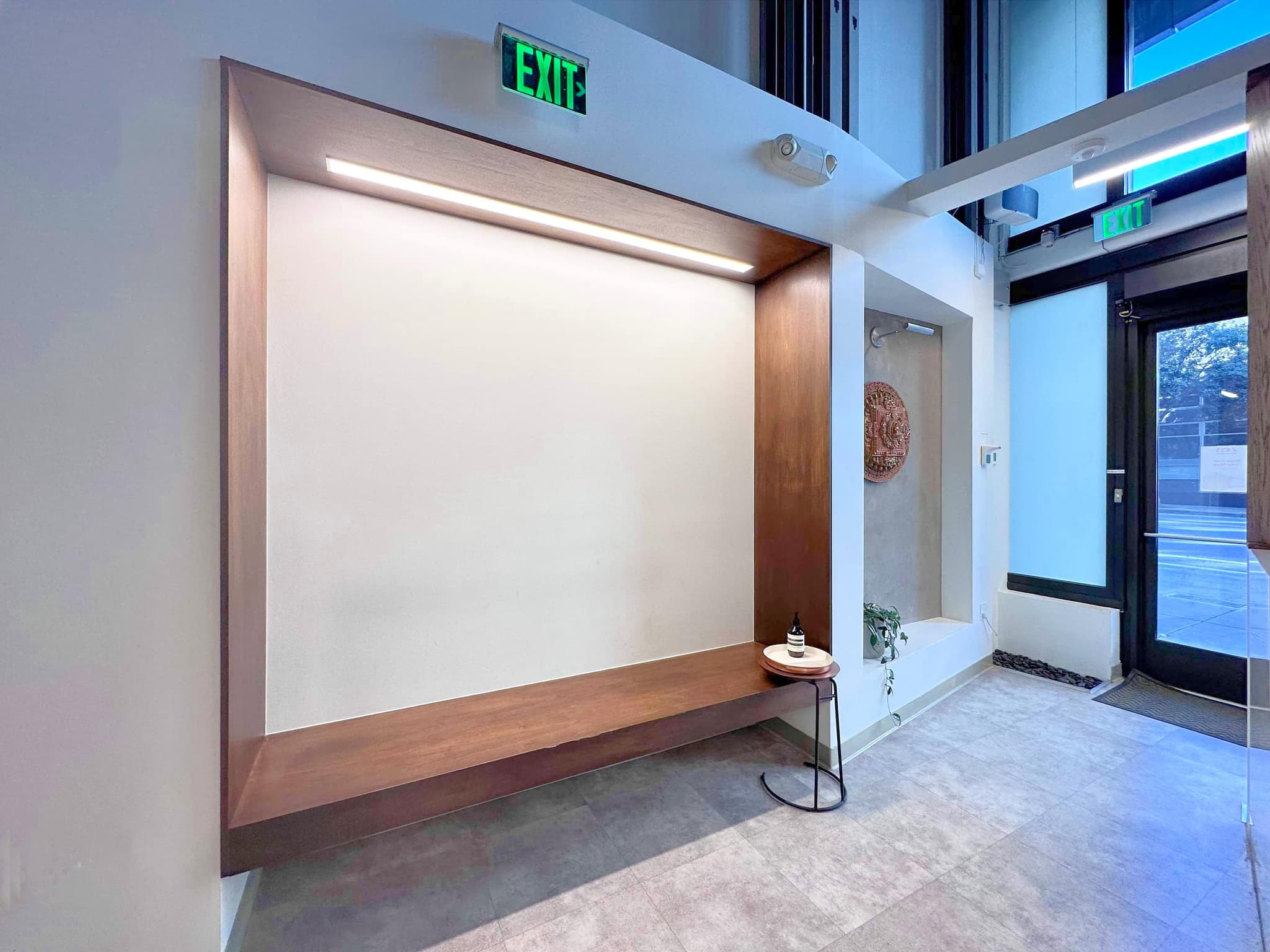 The walnut bench niche in the entry of the San Francisco studio, lit by a warm strip light, with the carved mandala in the alcove beyond