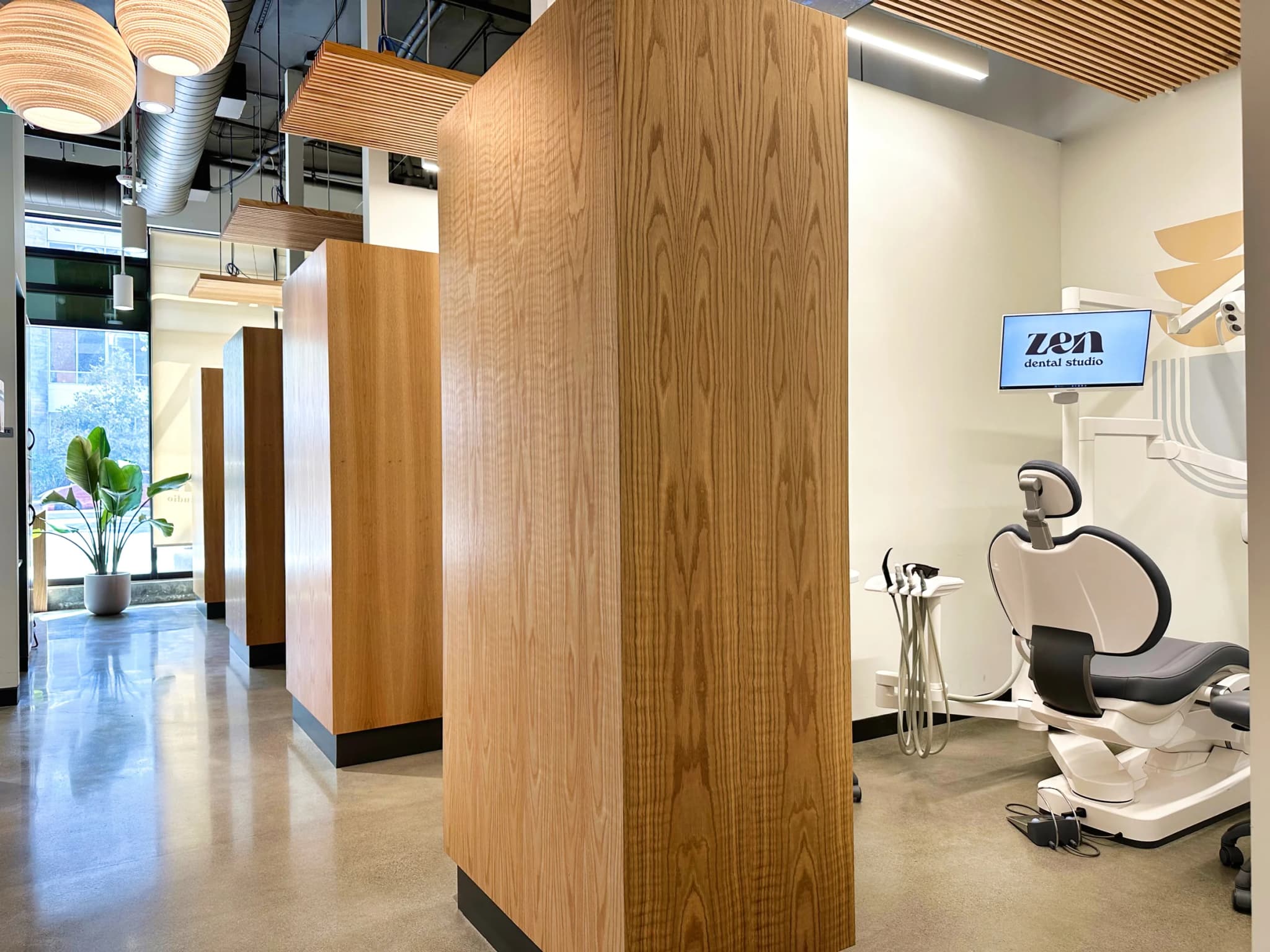 The Mountain View studio corridor under globe pendant lights, with an oak partition and a treatment room with its chair and screen