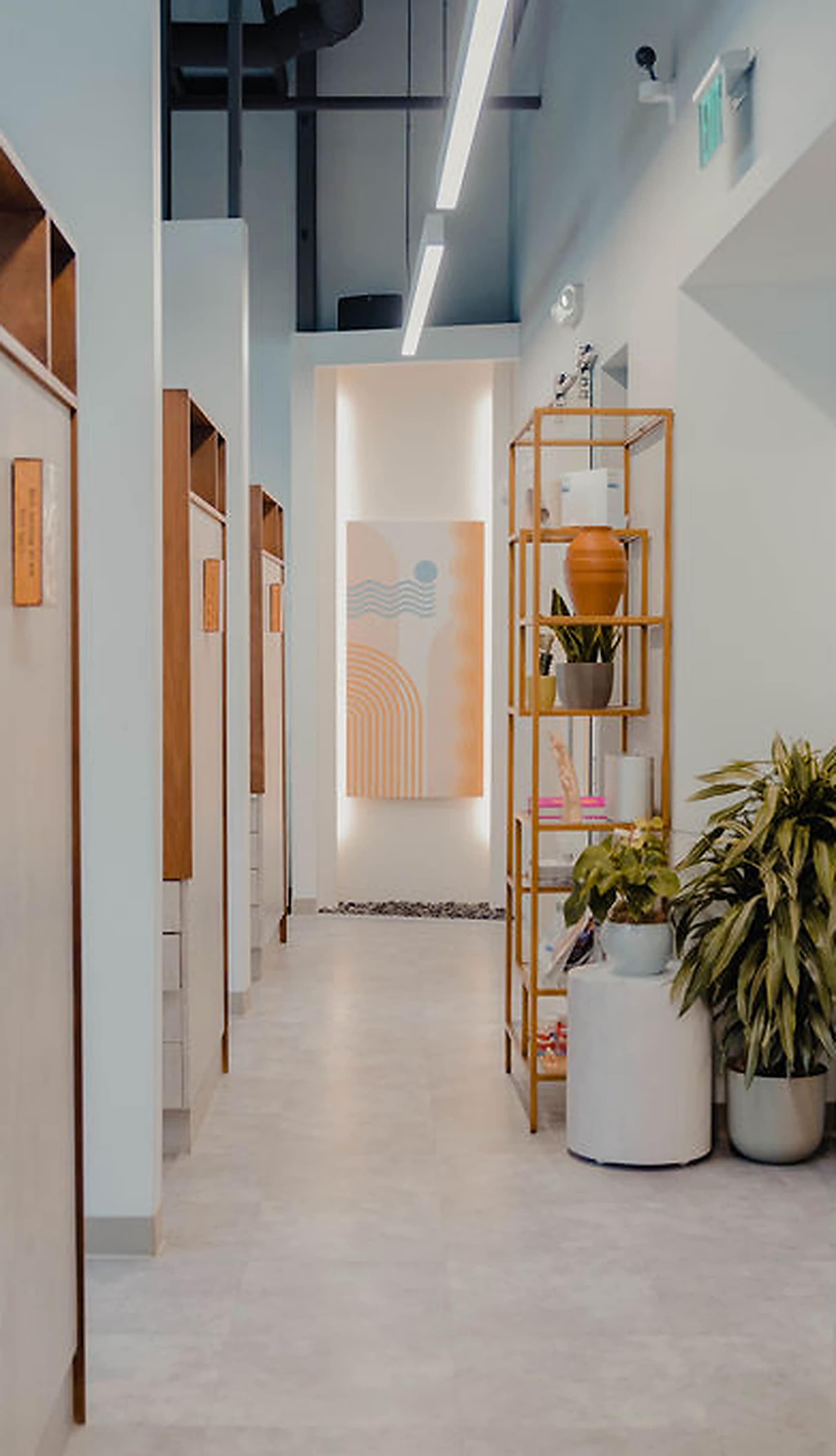The bright hallway of treatment suites at the San Francisco studio, with a pastel mural