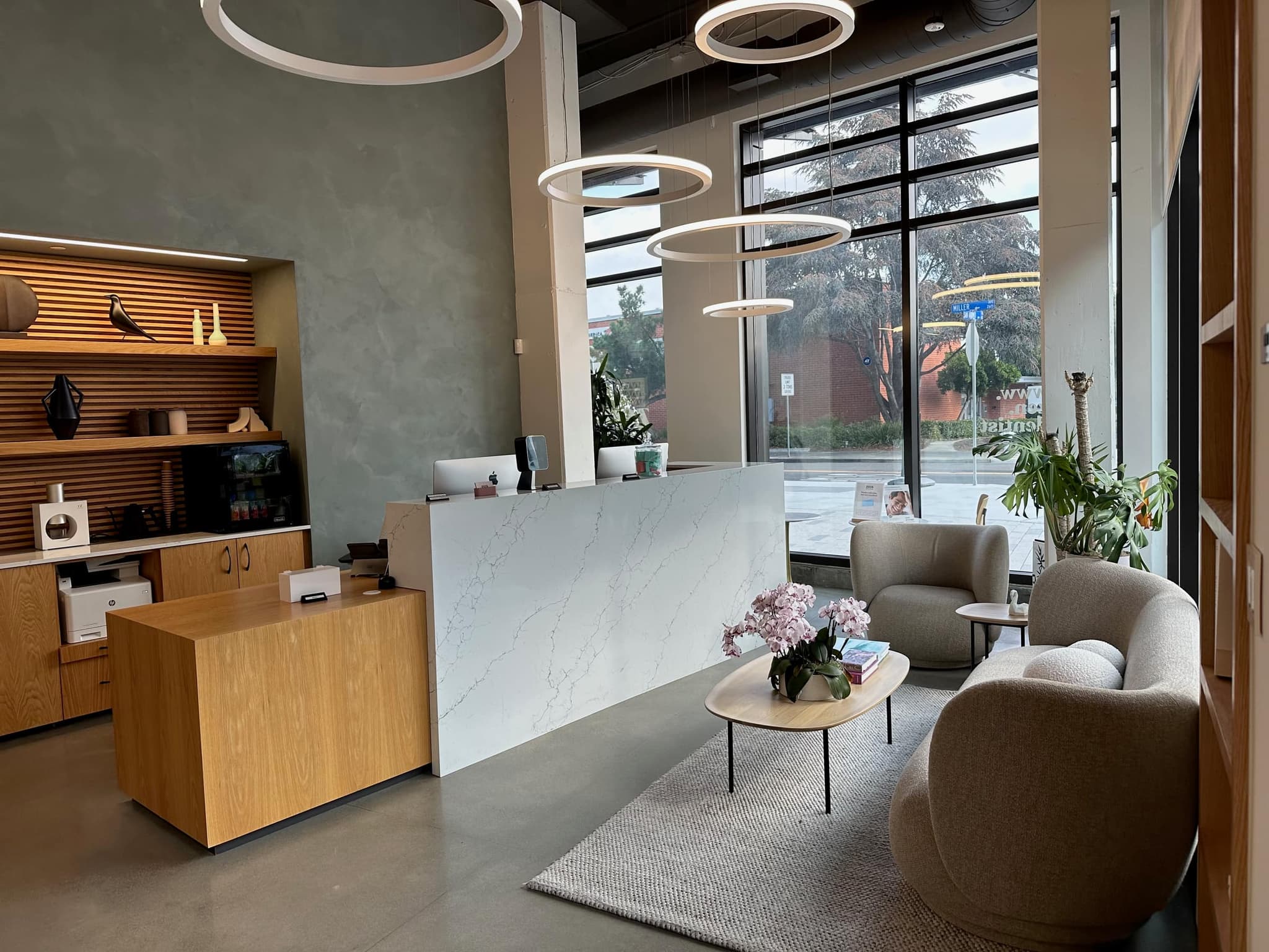 The light-filled reception and lounge, marble desk, ring pendants, and warm wood